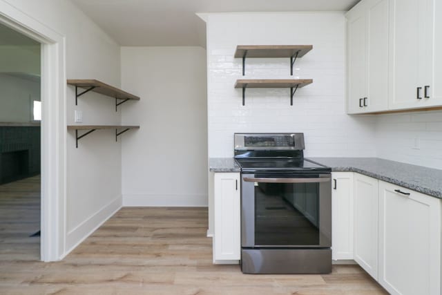 kitchen with stainless steel electric range oven, open shelves, stone countertops, and light wood-style flooring
