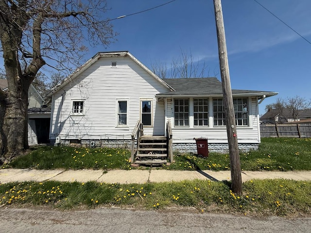 bungalow-style house featuring fence and roof with shingles