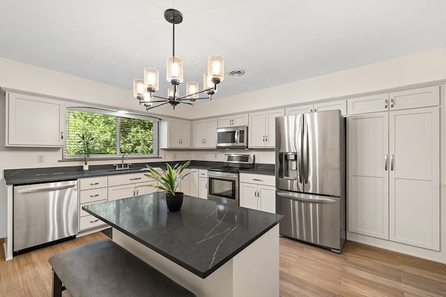 kitchen with sink, a kitchen island, light hardwood / wood-style floors, white cabinetry, and stainless steel appliances