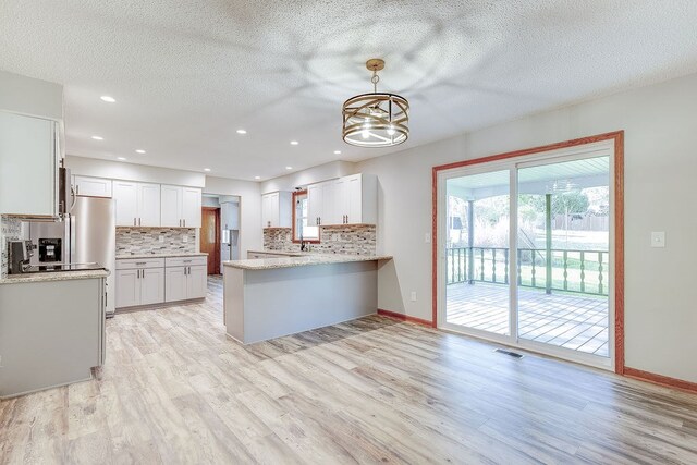 42 Kester Dr, Mount Vernon, OH 43050 - kitchen featuring decorative backsplash, a peninsula, light wood-style flooring, a chandelier, and a textured ceiling