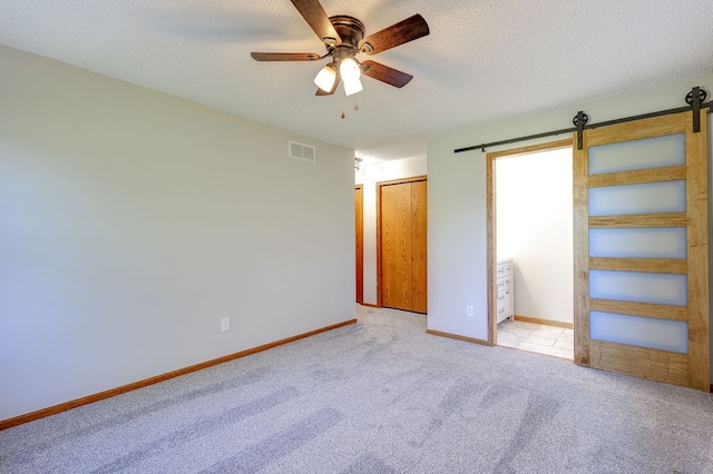 42 Kester Dr, Mount Vernon, OH 43050 - unfurnished bedroom with carpet floors, a barn door, baseboards, a textured ceiling, and a ceiling fan