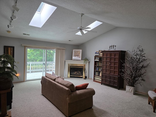 1683 Riva Ridge Dr, Mansfield, OH 44904 - carpeted living room featuring a skylight, a glass covered fireplace, vaulted ceiling, a ceiling fan, and a textured ceiling