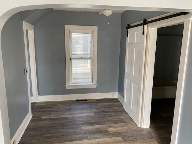 645 Wilson Ave, Marion, OH 43302 - interior space featuring baseboards, dark wood-style floors, a barn door, lofted ceiling, and arched walkways