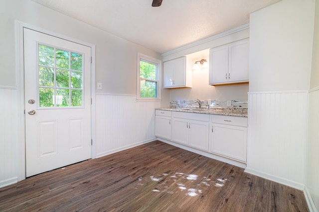 kitchen with light stone counters, sink, white cabinets, and plenty of natural light