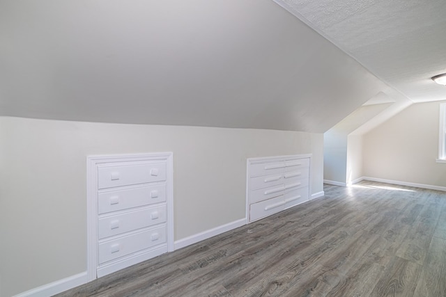 additional living space with wood-type flooring, lofted ceiling, and a textured ceiling