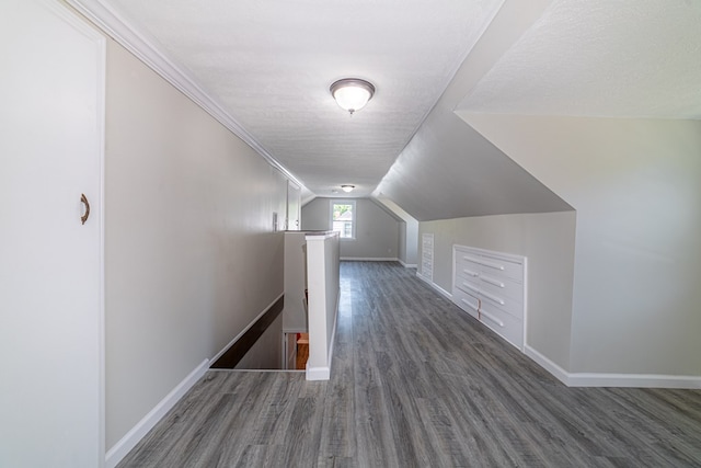 corridor with dark hardwood / wood-style flooring, a textured ceiling, ornamental molding, and lofted ceiling