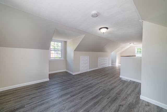 bonus room with dark hardwood / wood-style floors, a textured ceiling, and vaulted ceiling