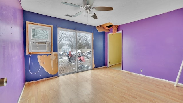 unfurnished room with visible vents, a ceiling fan, wood finished floors, cooling unit, and baseboards