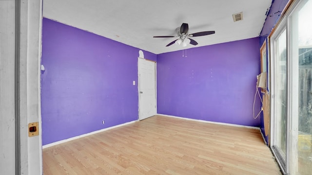 spare room with a ceiling fan, wood finished floors, visible vents, and baseboards