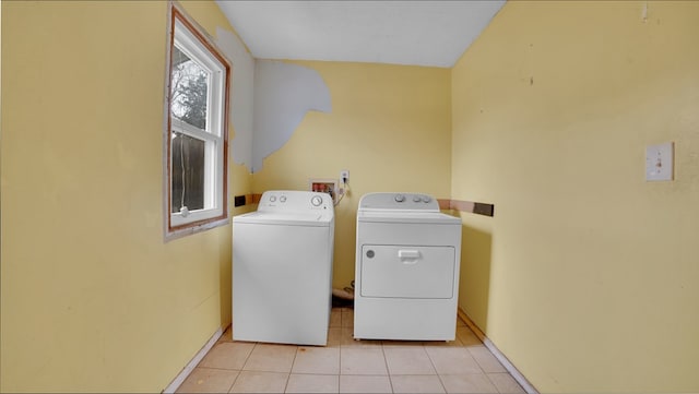 washroom featuring light tile patterned floors, baseboards, laundry area, and washer and clothes dryer