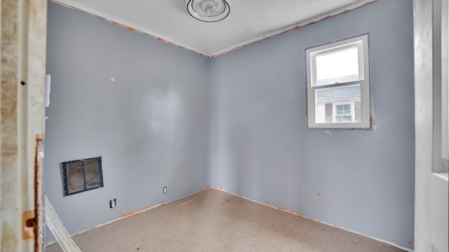 carpeted empty room featuring visible vents and a textured ceiling