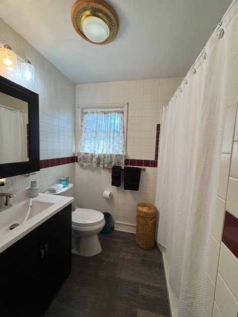 full bathroom with toilet, tile walls, vanity, and wood finished floors