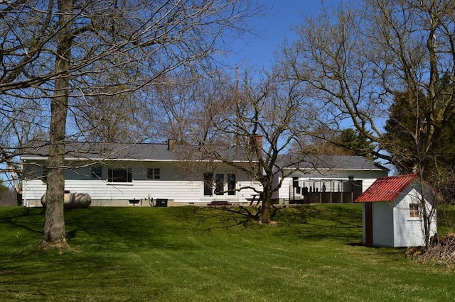 back of house featuring a lawn, an outdoor structure, a chimney, and a shed