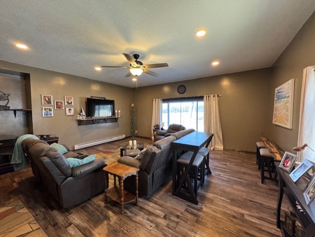 living area featuring dark wood finished floors, recessed lighting, ceiling fan, a textured ceiling, and a baseboard heating unit