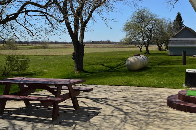 view of property's community featuring a patio, a rural view, and a lawn