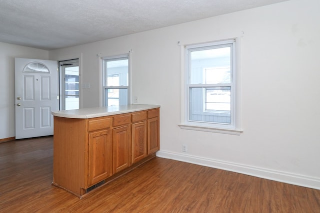 kitchen with a textured ceiling, kitchen peninsula, a wealth of natural light, and dark hardwood / wood-style floors