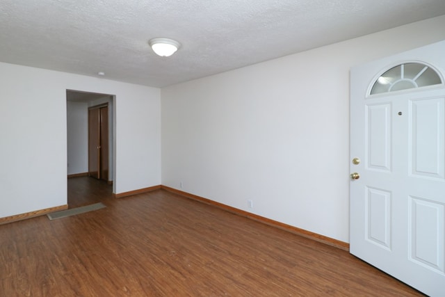 unfurnished room with dark hardwood / wood-style flooring and a textured ceiling