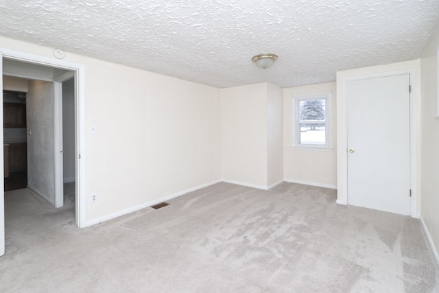 carpeted spare room with a textured ceiling