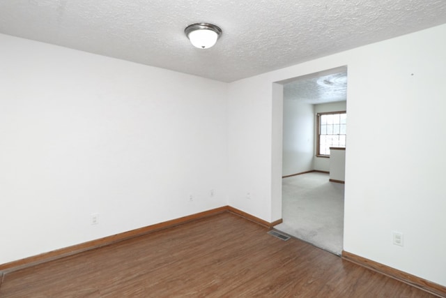 spare room with wood-type flooring and a textured ceiling