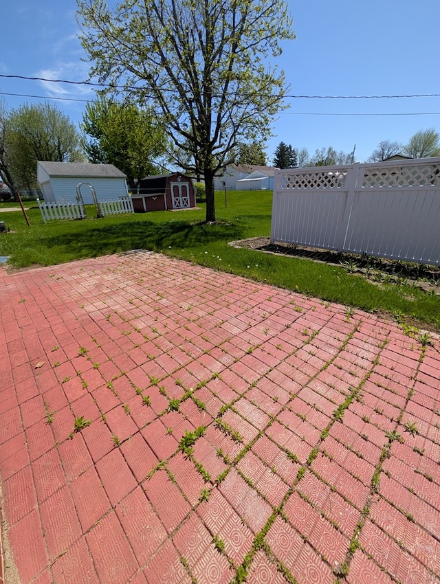 view of patio featuring an outbuilding, a shed, and fence
