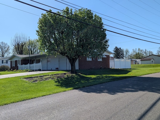 view of front facade with driveway, fence, brick siding, and a front lawn