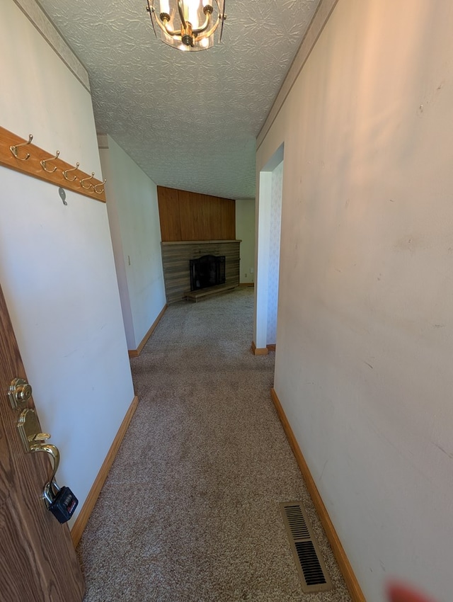 corridor featuring baseboards, visible vents, a textured ceiling, and light colored carpet
