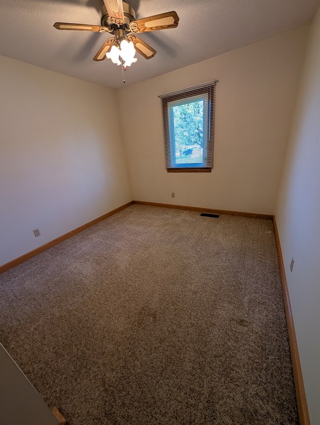 carpeted spare room featuring visible vents, ceiling fan, and baseboards