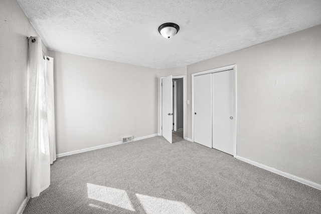 unfurnished bedroom featuring baseboards, visible vents, carpet floors, a closet, and a textured ceiling