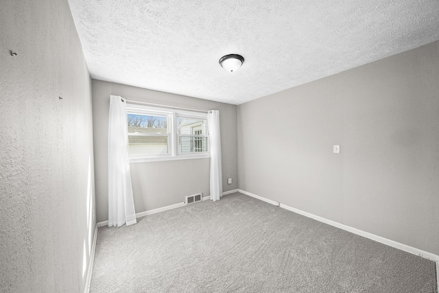 carpeted spare room featuring baseboards, visible vents, a textured wall, and a textured ceiling