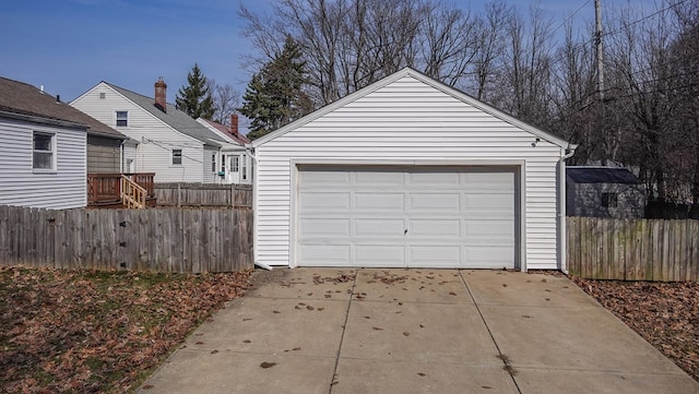 garage featuring concrete driveway and fence