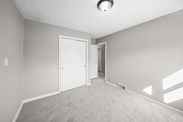 unfurnished bedroom with a closet, visible vents, a textured ceiling, and carpet