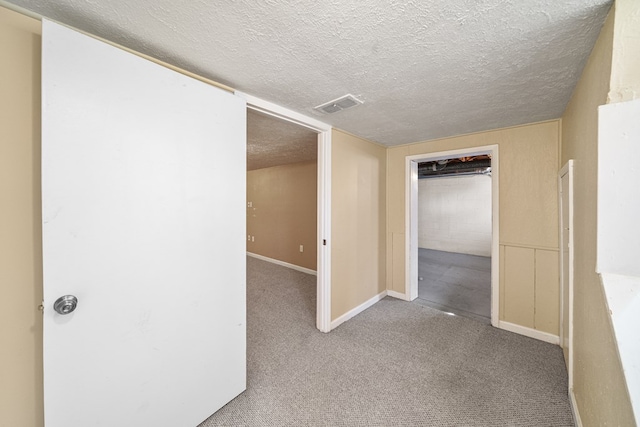 empty room with visible vents, carpet flooring, a textured ceiling, and baseboards