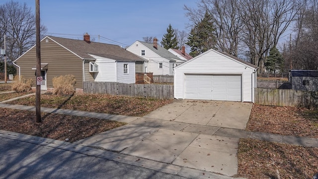 view of property exterior featuring an outbuilding, an AC wall unit, fence, and a detached garage