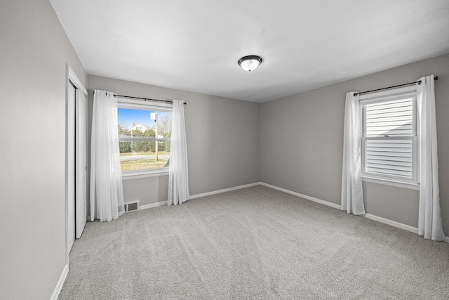 carpeted empty room featuring visible vents and baseboards