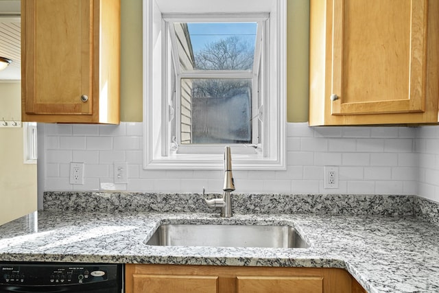 kitchen featuring decorative backsplash, dishwasher, light stone countertops, and a sink