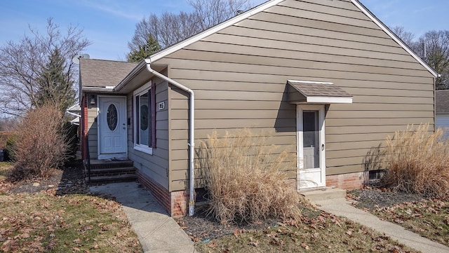 view of property exterior with crawl space and a shingled roof