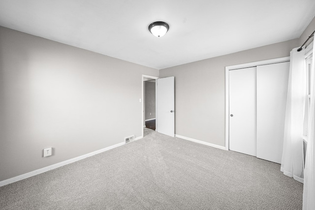 unfurnished bedroom with carpet flooring, baseboards, visible vents, and a closet