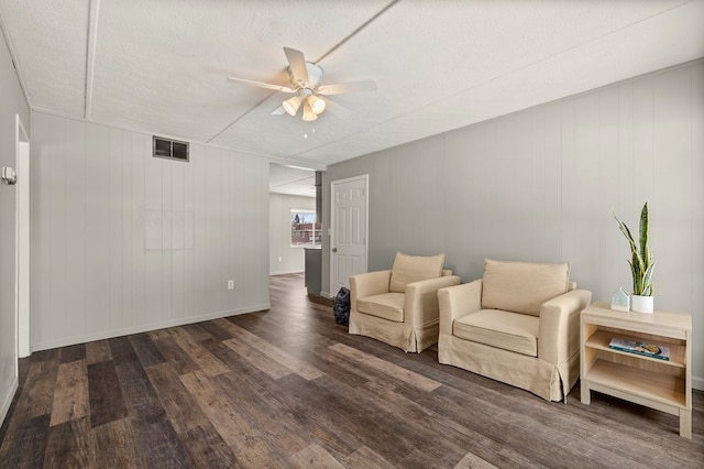 living area featuring dark wood-style floors, visible vents, a ceiling fan, a textured ceiling, and baseboards