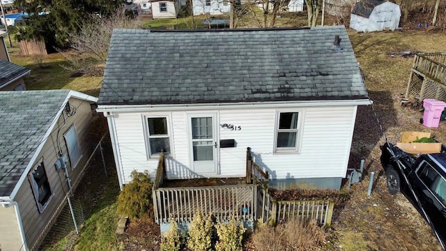 exterior space with a shingled roof and fence