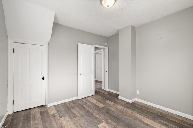 unfurnished bedroom with a textured ceiling, baseboards, and wood finished floors