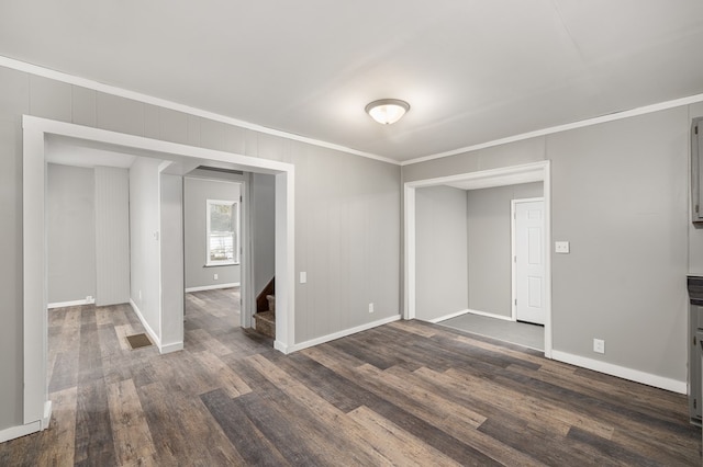 empty room with stairs, ornamental molding, dark wood-style flooring, and visible vents