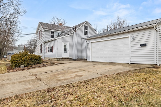 view of side of home with driveway, a garage, a chimney, and metal roof