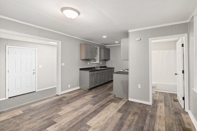 kitchen featuring a sink, ornamental molding, gray cabinets, and dark wood finished floors