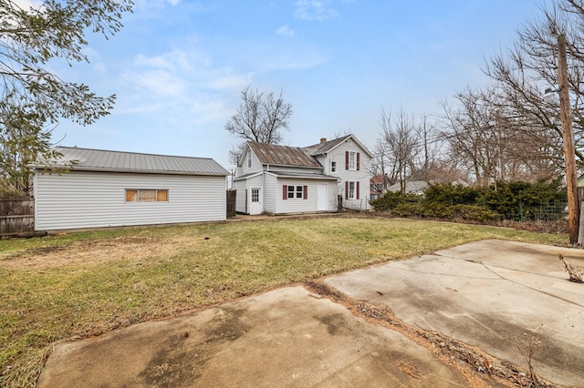 rear view of house with metal roof, a yard, a chimney, and fence