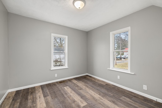 empty room featuring baseboards, wood finished floors, visible vents, and a healthy amount of sunlight