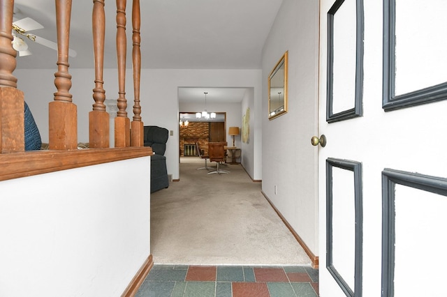 hallway with an inviting chandelier and dark colored carpet