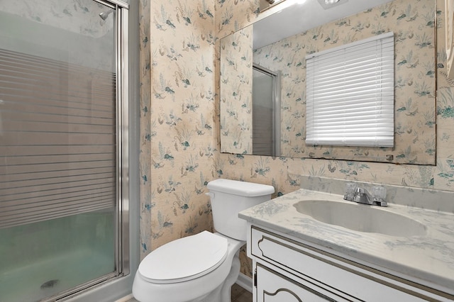 bathroom featuring vanity, a shower with shower door, and toilet