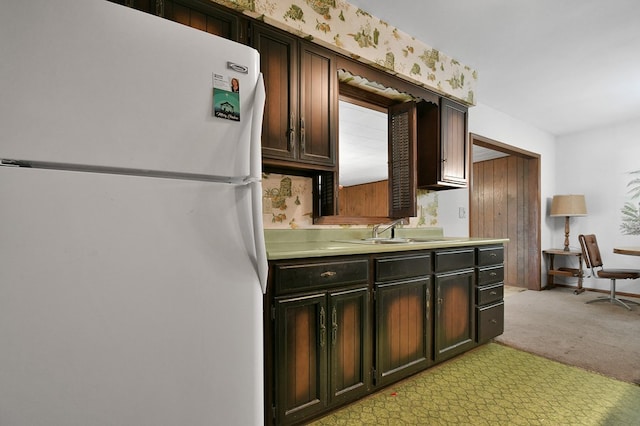 kitchen with light carpet, sink, dark brown cabinets, and white fridge