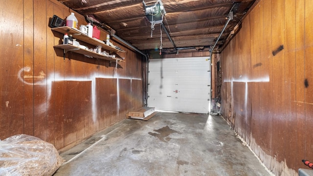 garage featuring a garage door opener and wooden walls