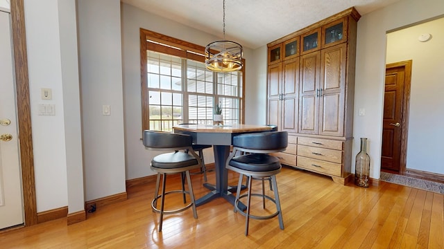dining room featuring light wood-style floors, baseboards, and a notable chandelier